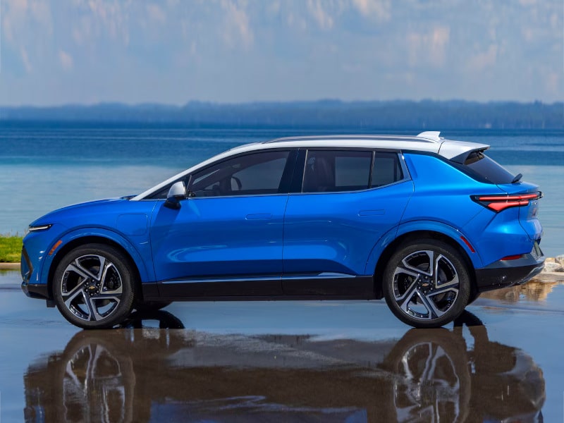 Blue SUV parked by a serene lake, reflecting its vibrant color and sleek design in the water.