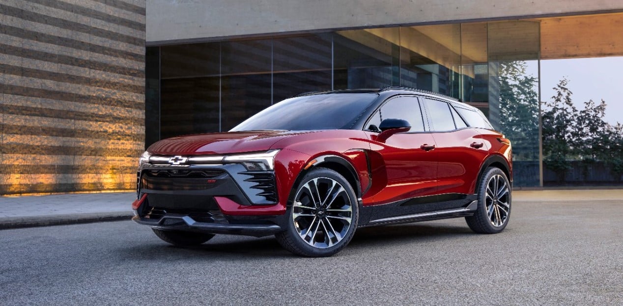 Red SUV parked in front of a modern glass building, showcasing sleek design and alloy wheels.
