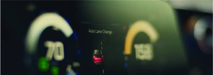 Car dashboard displaying auto lane change indicator and speedometer readings.