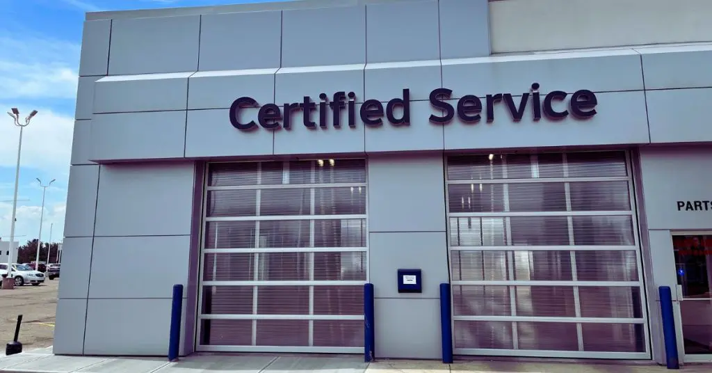 Exterior of a building with a sign reading "Certified Service" above large garage doors, implying automotive service facilities.