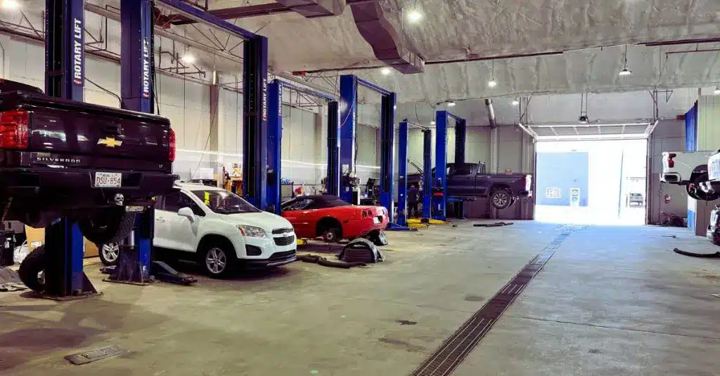 Auto repair shop interior with vehicles on lifts, including a black truck, white car, and red sports car.