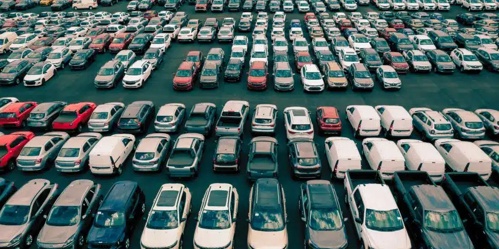 Parking lot filled with various cars in rows, showcasing diverse vehicle colors and models.
