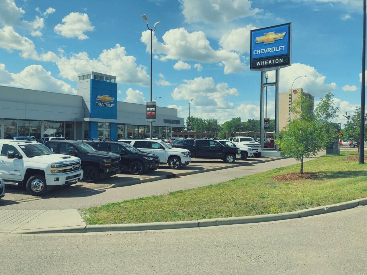 Chevrolet dealership with parked vehicles under a blue sky, featuring a prominent Chevrolet sign.