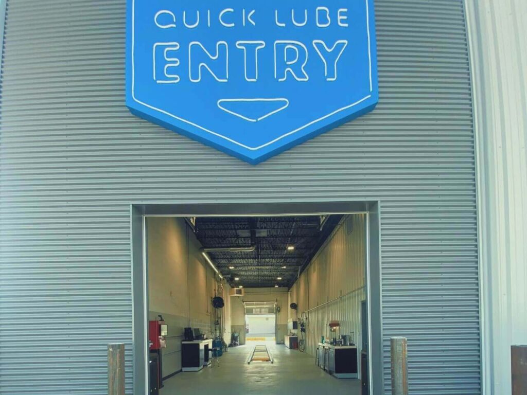 Blue "Quick Lube Entry" sign above garage entrance, showcasing an automotive service area.