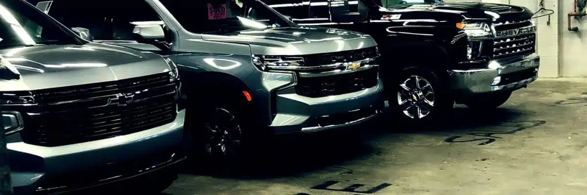 Three Chevrolet trucks parked indoors in a showroom setting, highlighting their front grills.