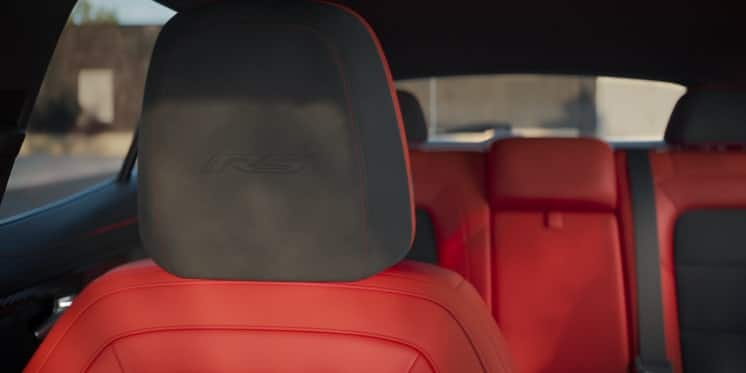 Front seat and backseat of a car with red leather upholstery and subdued lighting.