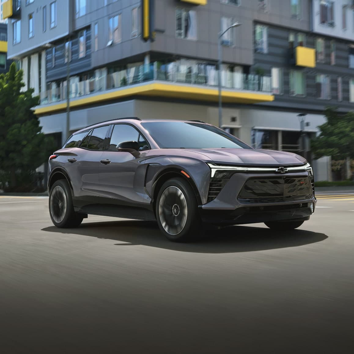 Sleek, modern SUV driving in an urban setting with a contemporary building backdrop.