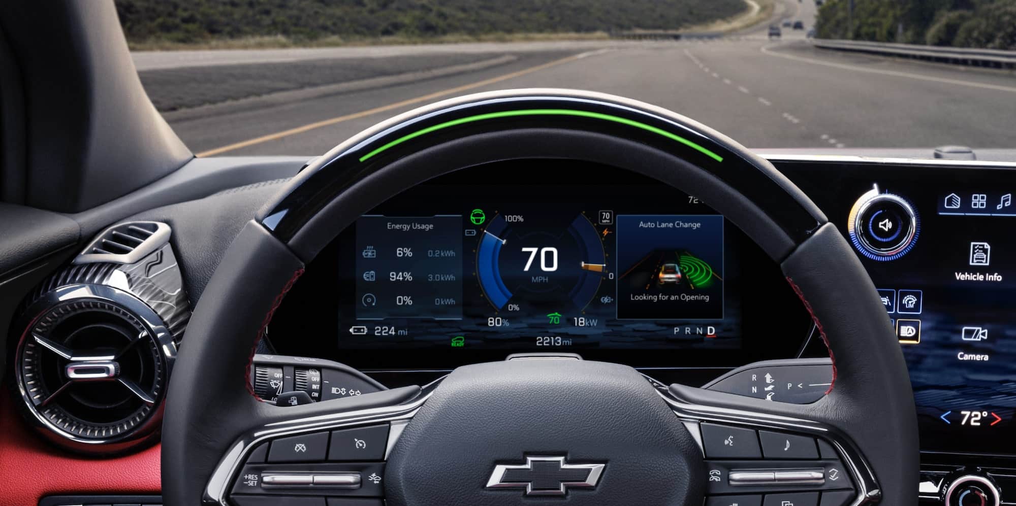 Modern car interior with red accents, digital displays, and vineyard view through the window.