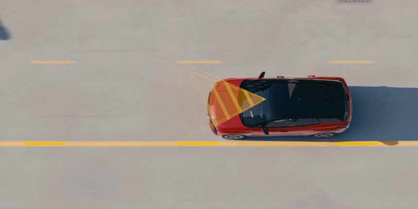 Red car with a highlighted sensor pattern driving on a road, showcasing advanced lane-keeping technology.